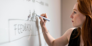 Frau arbeitet am Whiteboard und wertet Produktfeedback aus.